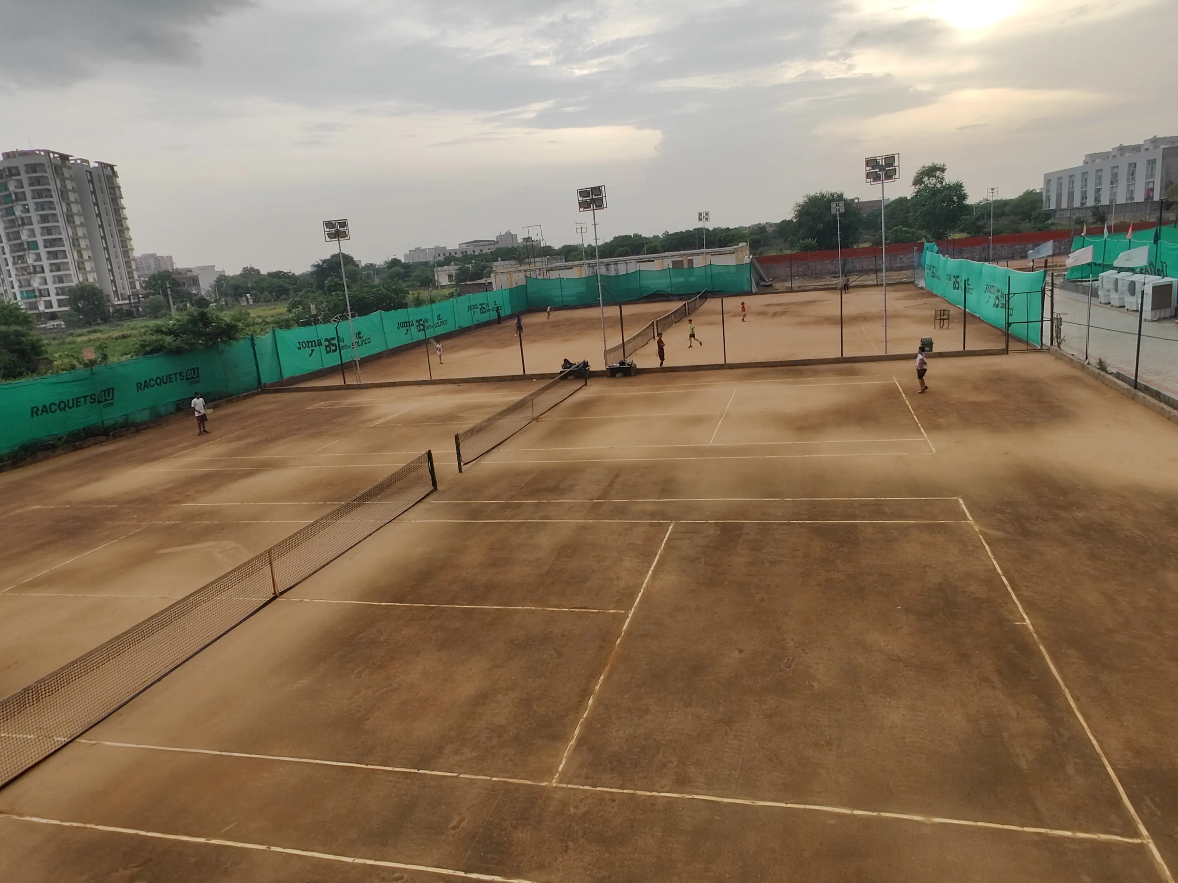 A tennis lesson in progress with a coach instructing a player on a sunny outdoor court.