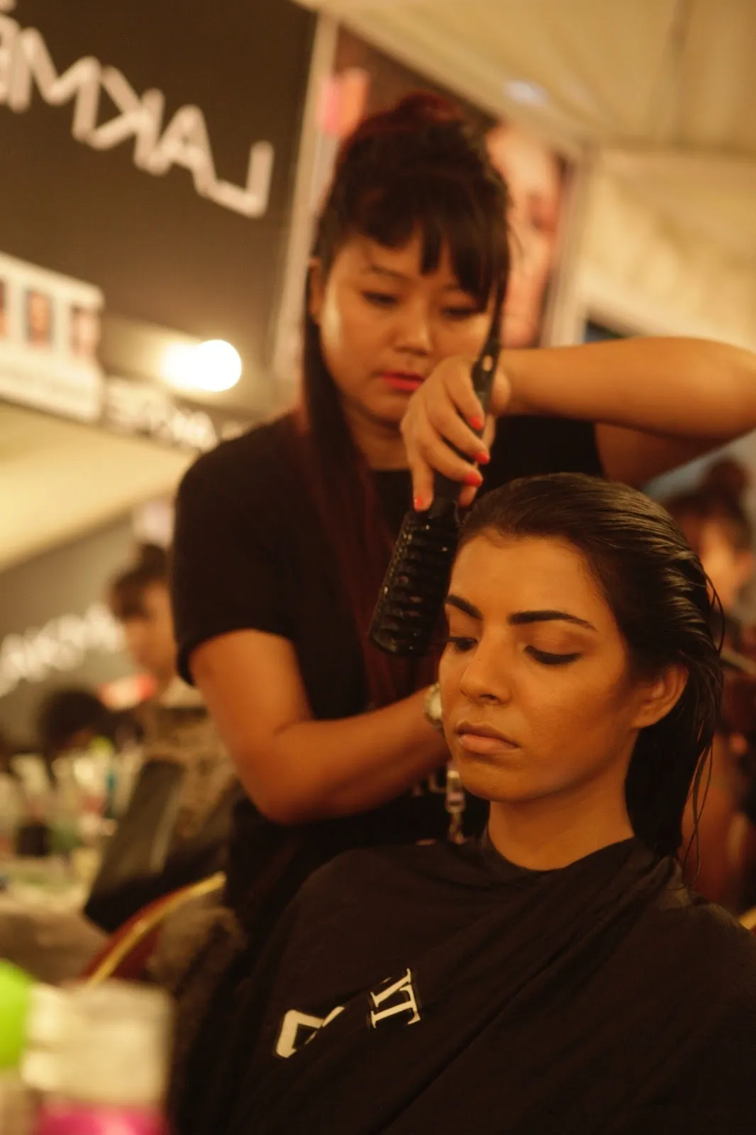 Smiling woman getting her hair styled at a salon by a professional hairdresser.