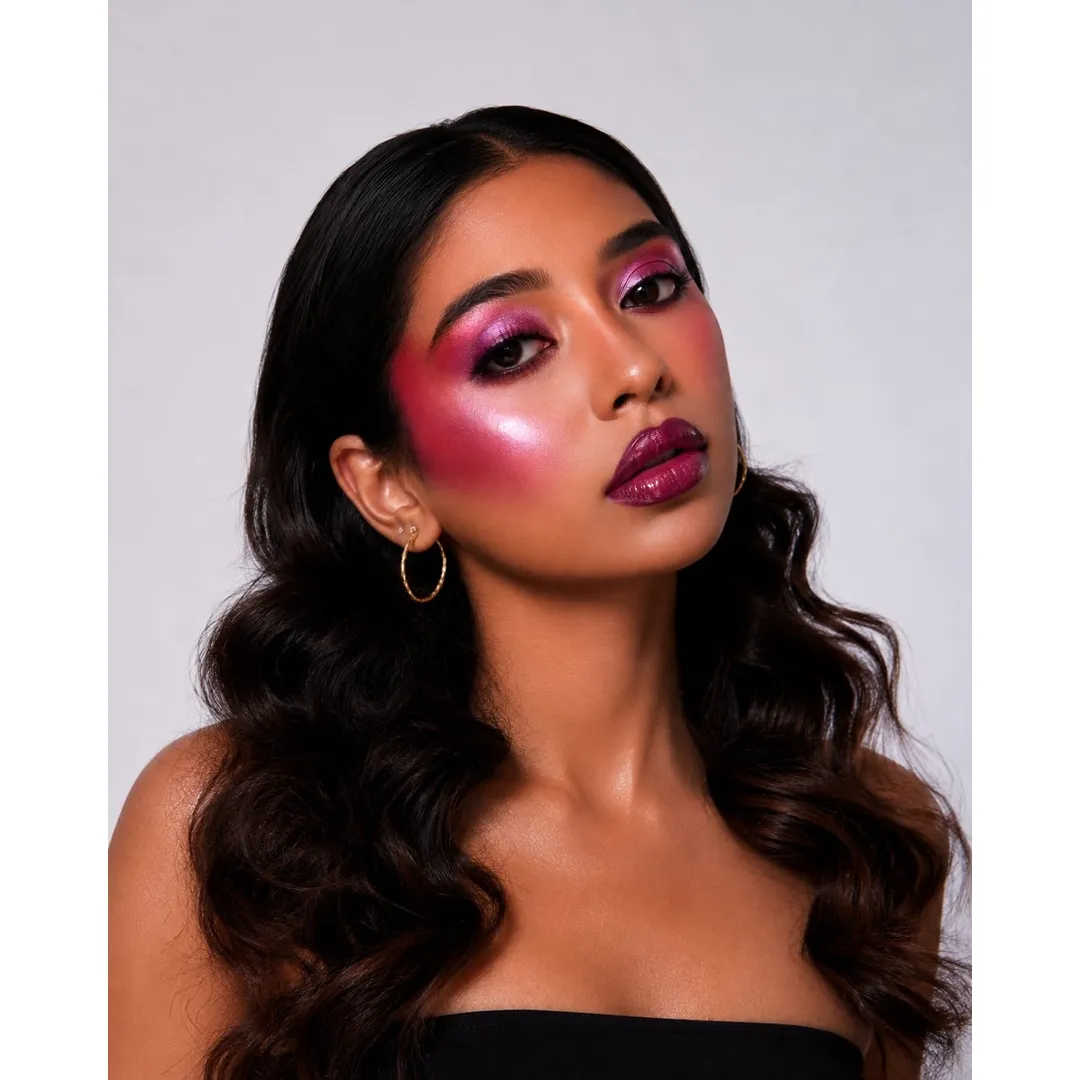 Close-up of a model with bold red makeup and dramatic lashes.