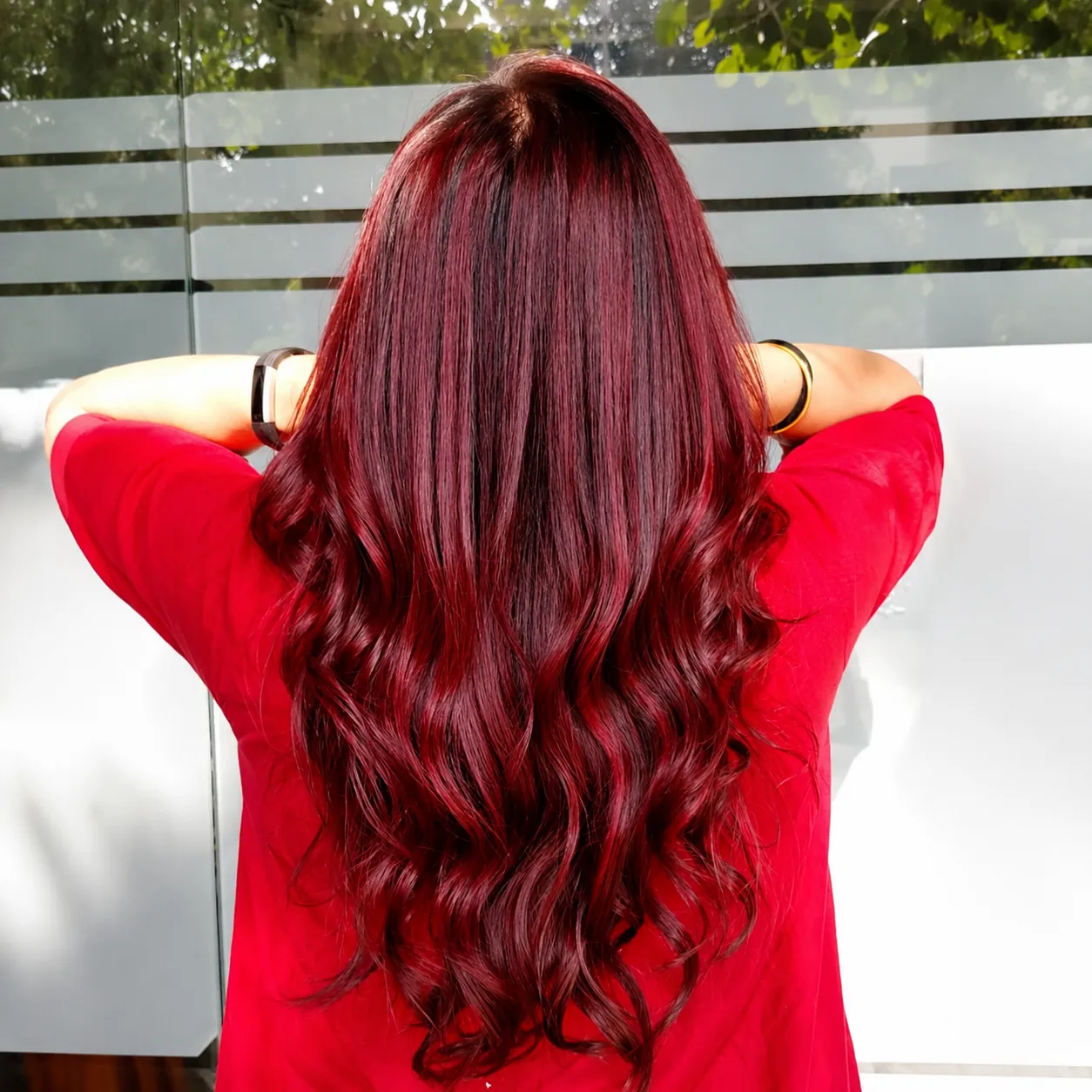 A side view portrait of a woman with light pink balayage hair on a minimalistic background.