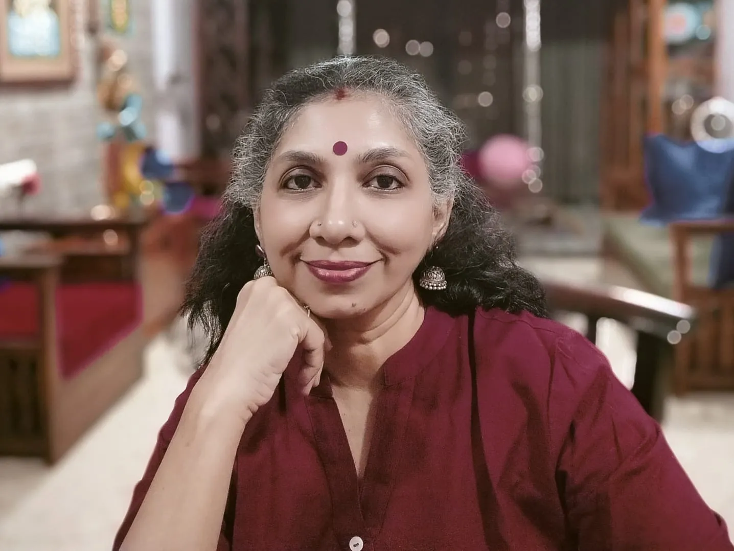 Smiling man in a formal vest and tie, arms crossed, exuding confidence.
