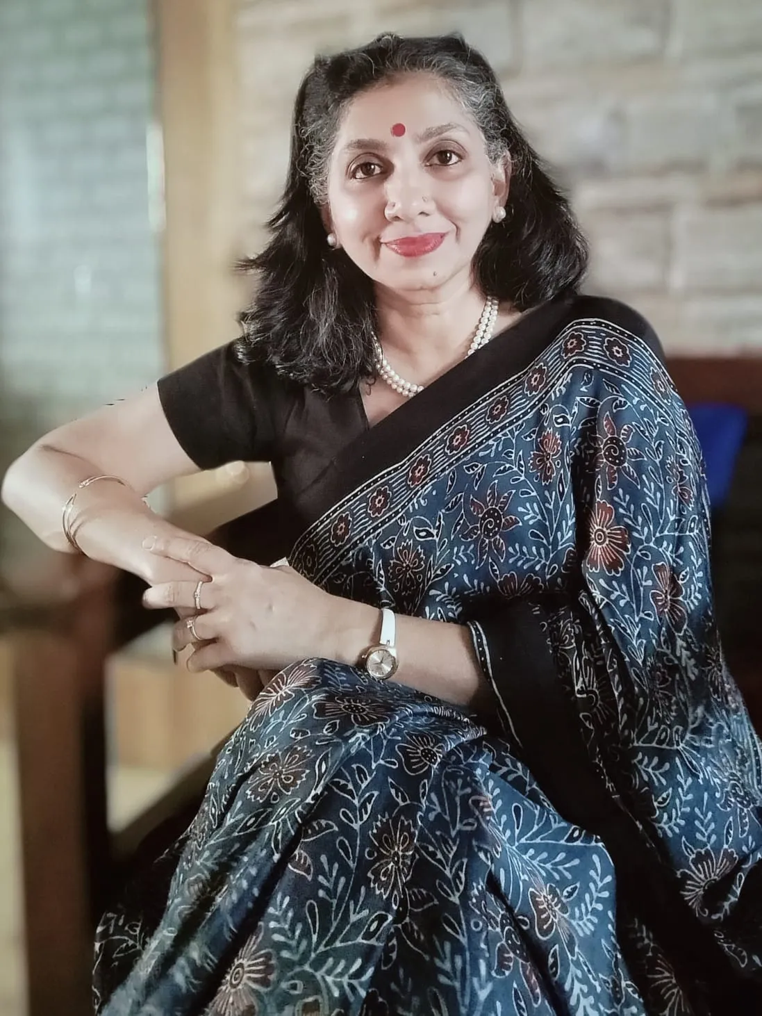 A smiling woman wearing glasses and a casual t-shirt poses joyfully.