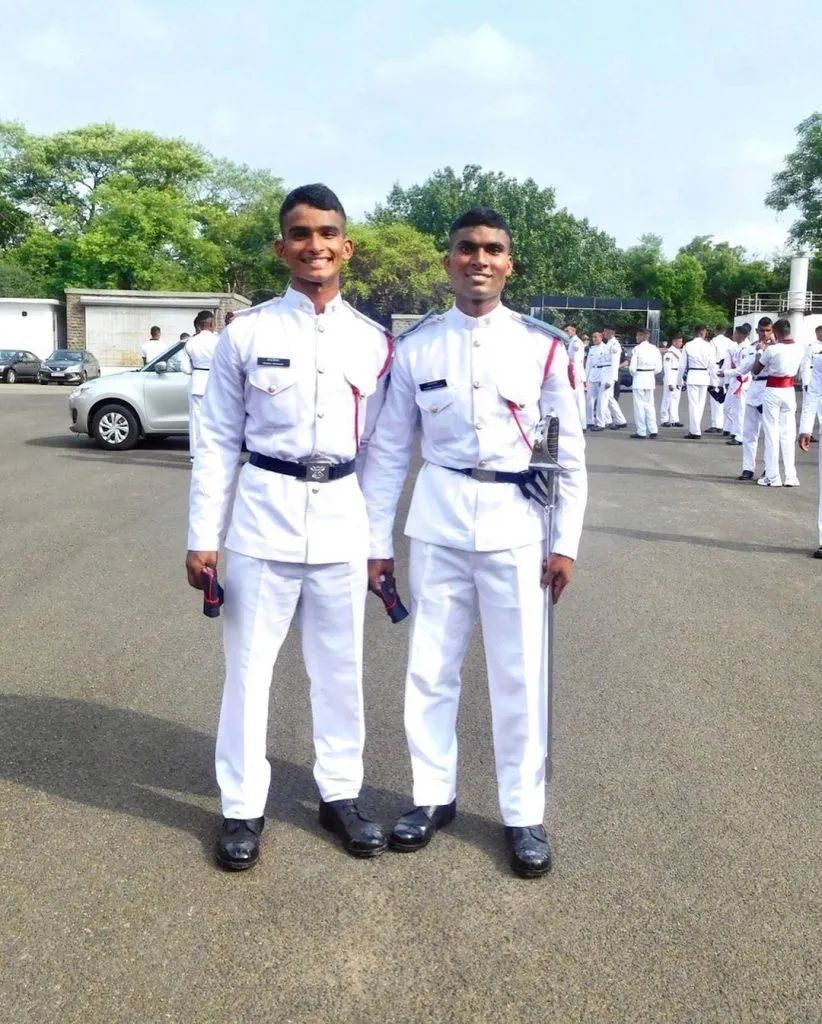 Two Asian teenagers holding diplomas and wearing medals, symbolizing academic success.